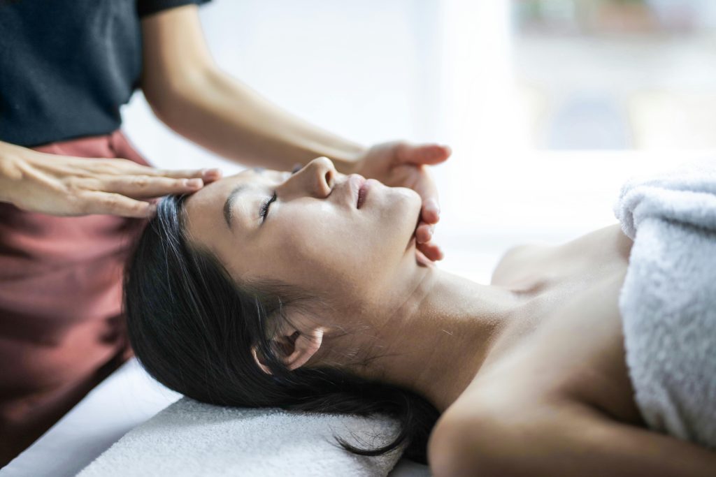 A serene spa treatment captures a woman receiving a soothing head massage indoors.