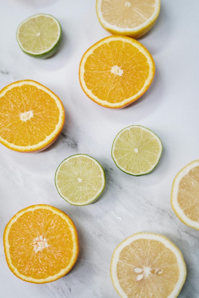 Vibrant flat lay of sliced oranges, lemons, and limes on marble, showcasing fresh and juicy textures.